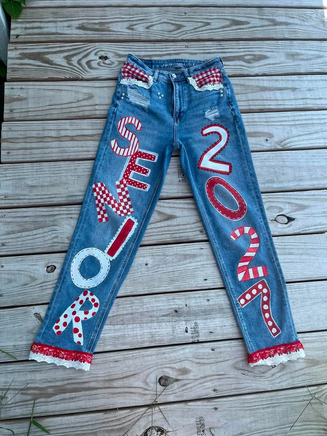 Denim jeans hand-lettered with a graduation year in red and white, finished with gingham ties and lace.